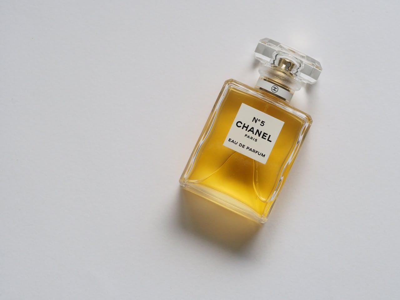 services-07 Elegant eau de parfum bottle with luxurious golden liquid on a minimalistic white background.